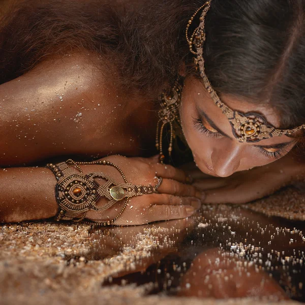 Beautiful girl in ethnic jewelry and mirror covered with sand — Stock Photo, Image