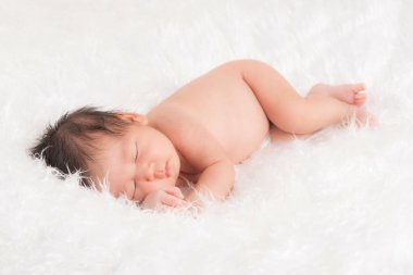 Sevimli yeni doğmuş erkek bebek yumuşak beyaz bir bez üzerinde uyur..