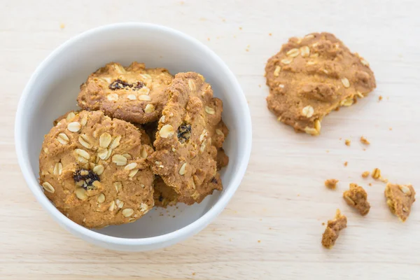 Cookie-kat, gabonafélék, fehér tálban törmelék az asztalon. — Stock Fotó