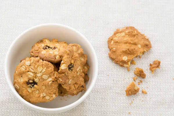 Cookie-kat, gabonafélék, fehér tálban törmelék az asztalon. — Stock Fotó