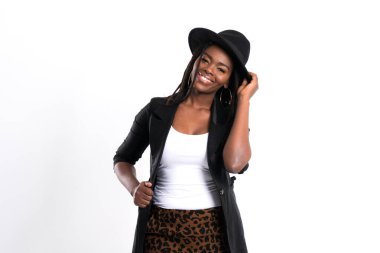 Rastalı ve fötr şapkalı Afro-Amerikan kadın portresi, beyaz arka plandaki stüdyo çekimlerine karşı geniş bir gülümsemeyle saf neşe ve güveni ifade ediyor..