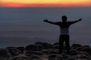 Sırtında siluet adam kolları açık olarak nodüler taşların zirvesinde duruyor ya da günbatımında Lan Hin Poom, Phitsanulok, Tayland 'da Phu Hin Rong Kla Milli Parkı, özgürlük kavramı