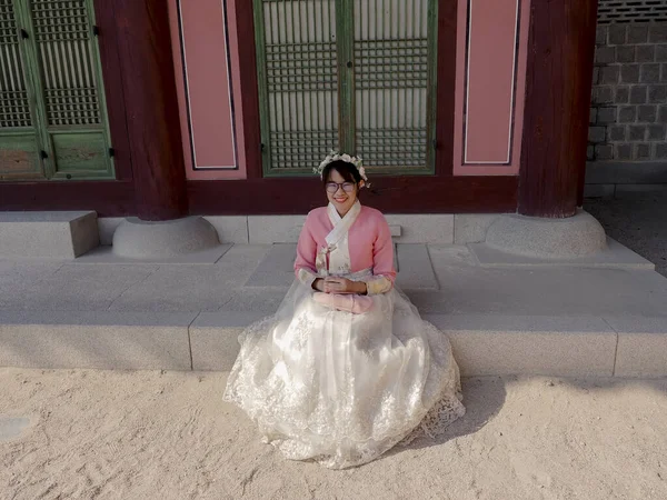 幸せなアジアの観光客の女性でピンク韓国の伝統的なドレスで歴史的な古代の建物 — ストック写真