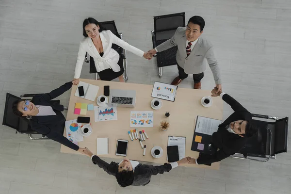 top view scene of diversity business people with formal wear standing and hold hand together around meeting table happy action for teamwork in  modern workplace, people business group, unity concept