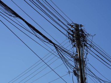 Elektrik direğindeki dağınık elektrik ve ağ hatları ve claer mavi gökyüzü arkaplanı