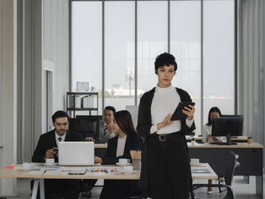 Tablet tutan zeki atraktif iş kadınlarının portresi ve çalışma ofisinde çeşitli insanlarla, kadın liderleriyle, iş analizleriyle ve strateji konseptiyle ileriye bakmak.