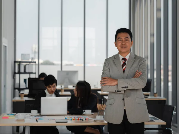 asian business man crossed arms and looking forward with confident in office with diversity people working, business team leader, success, analysis and strategy concept