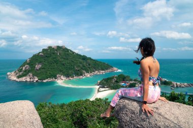 Kadın Nangyuan adasının tepesinde oturuyor ve rahatlıyor. Güzel denize bakıyor. Tayland, Suratthani 'de turistik bir yer.