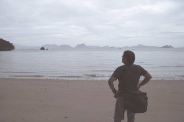 Sahilde yalnız kameraman, sakin bir sahile bakan adam.