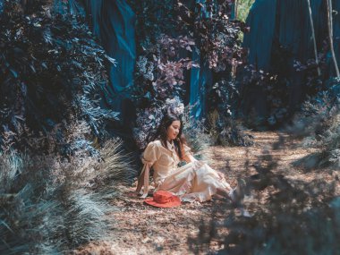 Asyalı kadın oturur ve mavi mağaranın fantezi renkli ormanlarında düşünür.