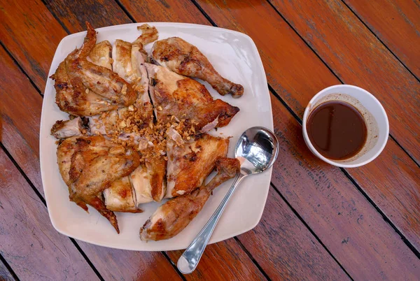 Kızarmış tavuk çeşnili kızarmış sarımsaklı baharatlı tatlı ve ekşi soslu ahşap masa.