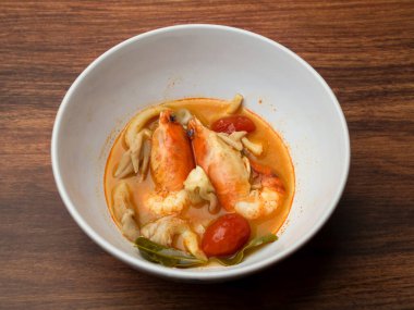 Tahta masada beyaz kase içinde sıcak ve baharatlı karides çorbası (Tayland yemeği Tom Yum Goong), ev yapımı yemek, şifalı karides.