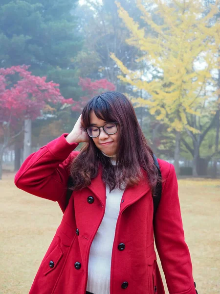 赤い秋のコートに眼鏡をかけたアジアの女性の肖像画落ち込んで悲しいと退屈 木の公園に立つ女性 — ストック写真
