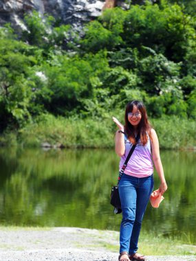 Asian woman standing near green forest lake bokeh background 