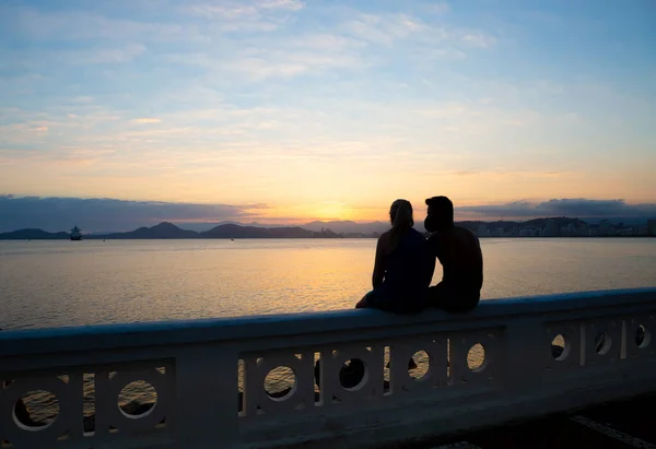 日没時のサントスの街の眺め 前景に自然を楽しむ短い壁に座っている焦点を当てていないカップル — ストック写真