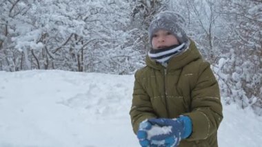 Çocuk tatilde kış parkında karla eğleniyor.