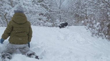 Çocuk tatilde kış parkında karla eğleniyor.