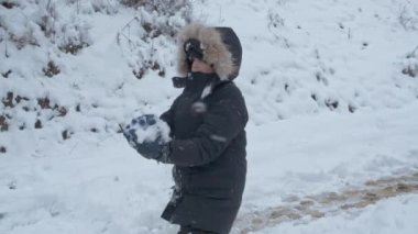 Çocuk tatilde kış parkında karla eğleniyor.