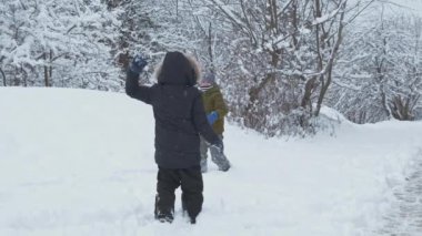 Çocuklar tatilde kış parkında karla eğleniyorlar.