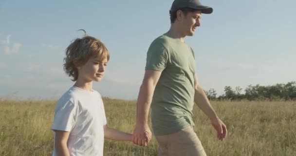 Glückliches Kind hält Väter beim Spazierengehen im Freien an der Hand — Stockvideo