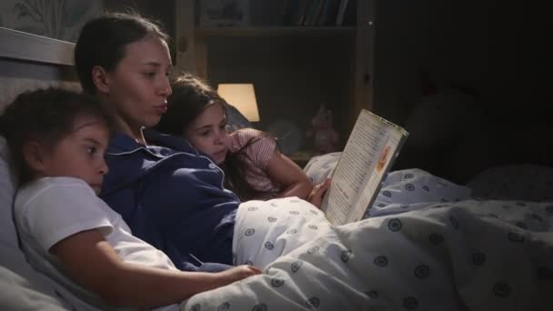 Young attractive mother reading book with fairy tales for children — Stock Video