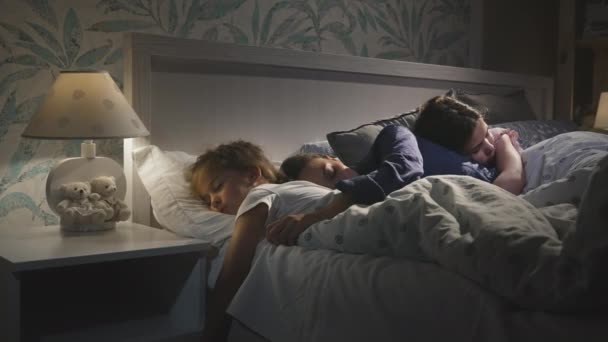 Young attractive mother sleeping with children, daughters together. — Stock Video