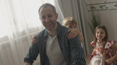 Gülümseyen baba evde tatlı çocuklarla eğleniyor.