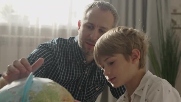 Glücklicher Vater und kleiner Junge mit Blick auf Globus, — Stockvideo