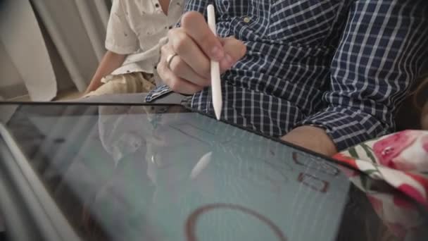 Far med barn som tegner på bærbar enhet hjemme – stockvideo