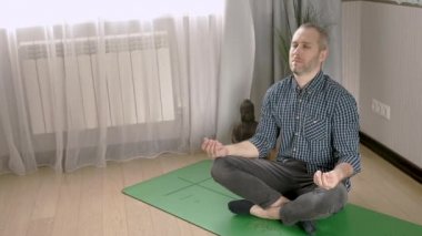 Sakin genç adam oturma odasında meditasyon yapıyor.