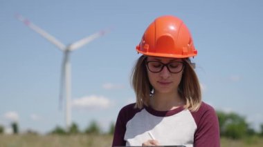 Rüzgar türbini elektrik endüstrisinde çalışan kadın mühendis. Rüzgar türbinlerinin arka planında tablet kullanan kadın işçi. Ekolojik enerji, endüstri gücü, yel değirmeni, tarla işçisi yenilenebilir