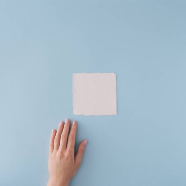 Beyaz kağıt kart ve pastel mavi arka plandaki el. Minimum düzlük.
