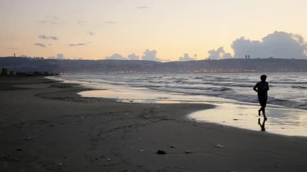 Mann läuft bei Sonnenuntergang an der Küste entlang — Stockvideo