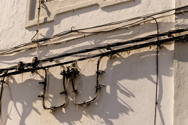 Stromkabel hängen über einer Wand — Stockfoto