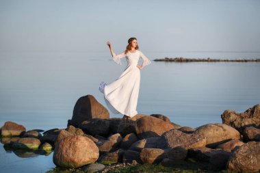 Uzun beyaz elbiseli güzel, narin kız gelin... Akşamları deniz kıyısındaki taşların üzerinde duruyor..