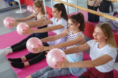 Spor salonunda toplarla spor yapan bir grup genç kız..