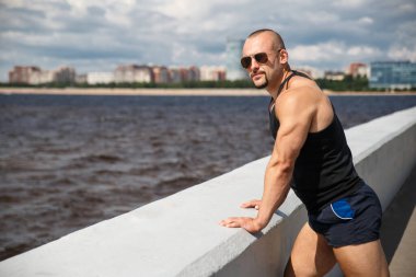 Atletik genç yakışıklı adam güneşli bir yaz gününde Finlandiya Körfezi 'nin setinde, St. Petorbugr, Rusya.