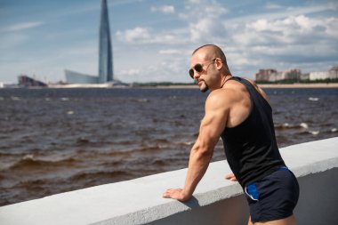 Atletik genç yakışıklı adam güneşli bir yaz gününde Finlandiya Körfezi 'nin setinde, St. Petorbugr, Rusya.