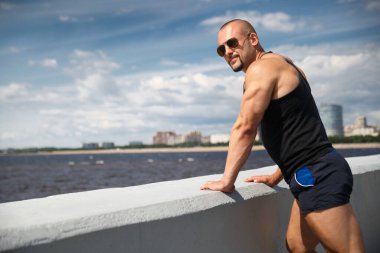 Atletik genç yakışıklı adam güneşli bir yaz gününde Finlandiya Körfezi 'nin setinde, St. Petorbugr, Rusya.