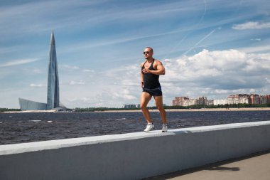 Atletik adam bir yaz günü rıhtımda koşuyor..