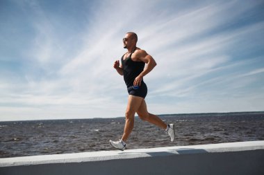 Atletik adam bir yaz günü rıhtımda koşuyor..