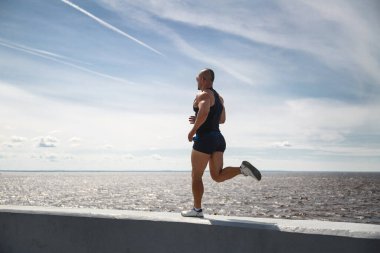 Atletik adam bir yaz günü rıhtımda koşuyor..