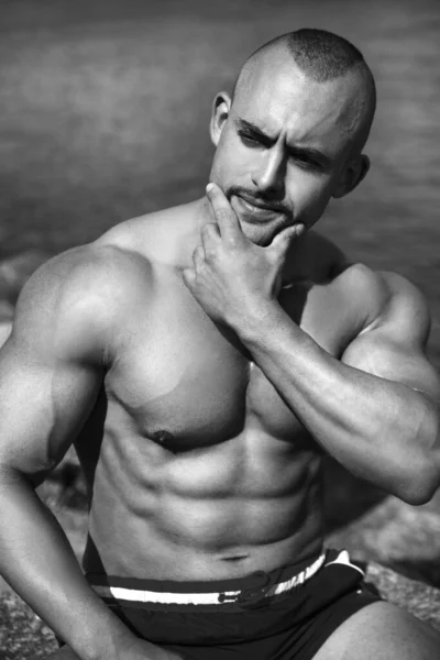 Black and white portrait of a sexy athletic male with a naked torso, outside.