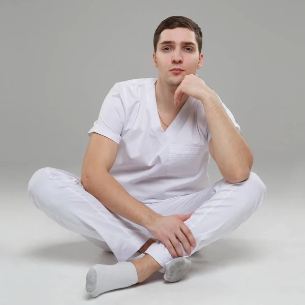 Young Man Medical Overalls Sits Gray Background — Stock Photo, Image