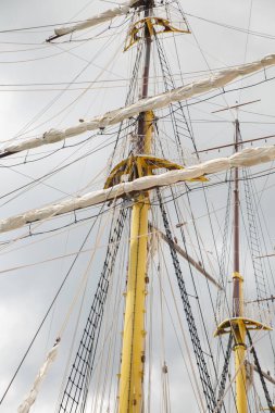 Bulutlu bir arka planda donanımlı yelkenli gemisinin direkleri..