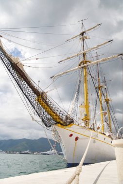 Denizin arka planında yelkenli gemi rıhtıma demirlemiş..