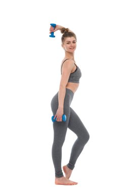 Elinde dambıllar olan zayıf bir kız beyaz bir arka planda izole edilmiş fitness ile meşgul..