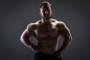 Arka planda çıplak gövdesi olan cesur atletik adam karanlık bir arka plana karşı..