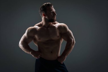 Arka planda çıplak gövdesi olan cesur atletik adam karanlık bir arka plana karşı..