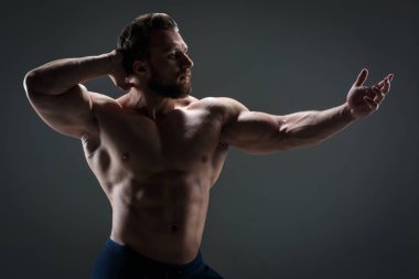 Arka planda çıplak gövdesi olan cesur atletik adam karanlık bir arka plana karşı..